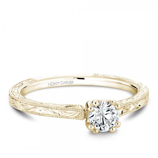 A Carver Studio engraved yellow gold engagement ring with a round center stone.
