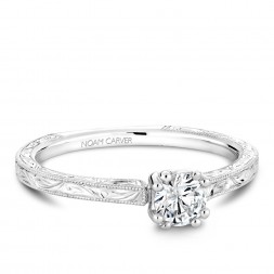 A Carver Studio engraved white gold engagement ring with a round center stone.
