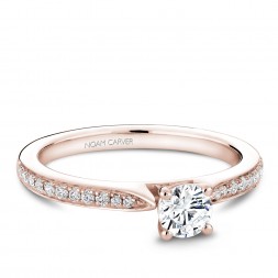 A solitaire Carver Studio rose gold engagement ring with a round center stone and 23 diamonds.